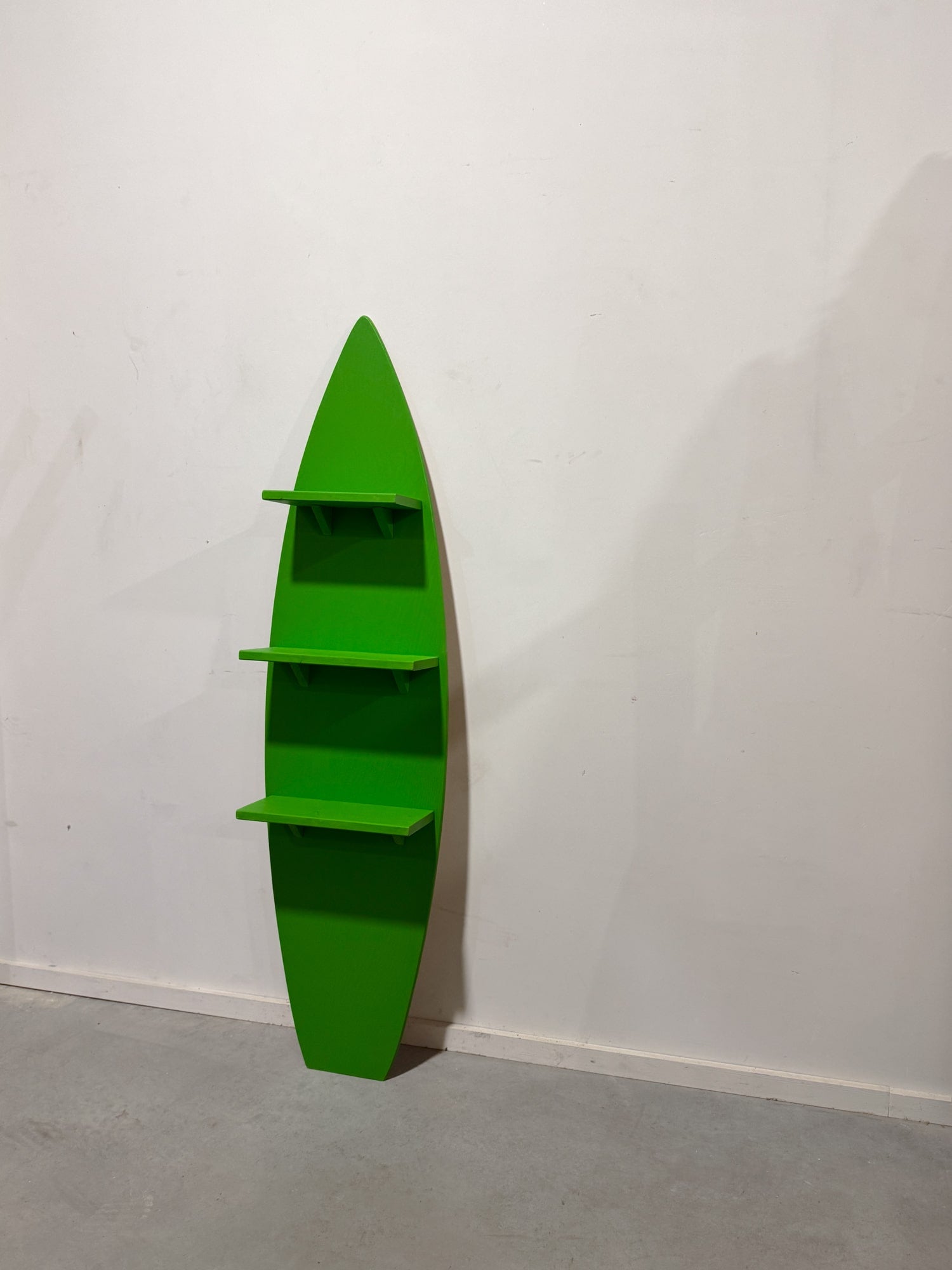 Eco-friendly green wooden surfboard converted into a functional three-tier shelving unit