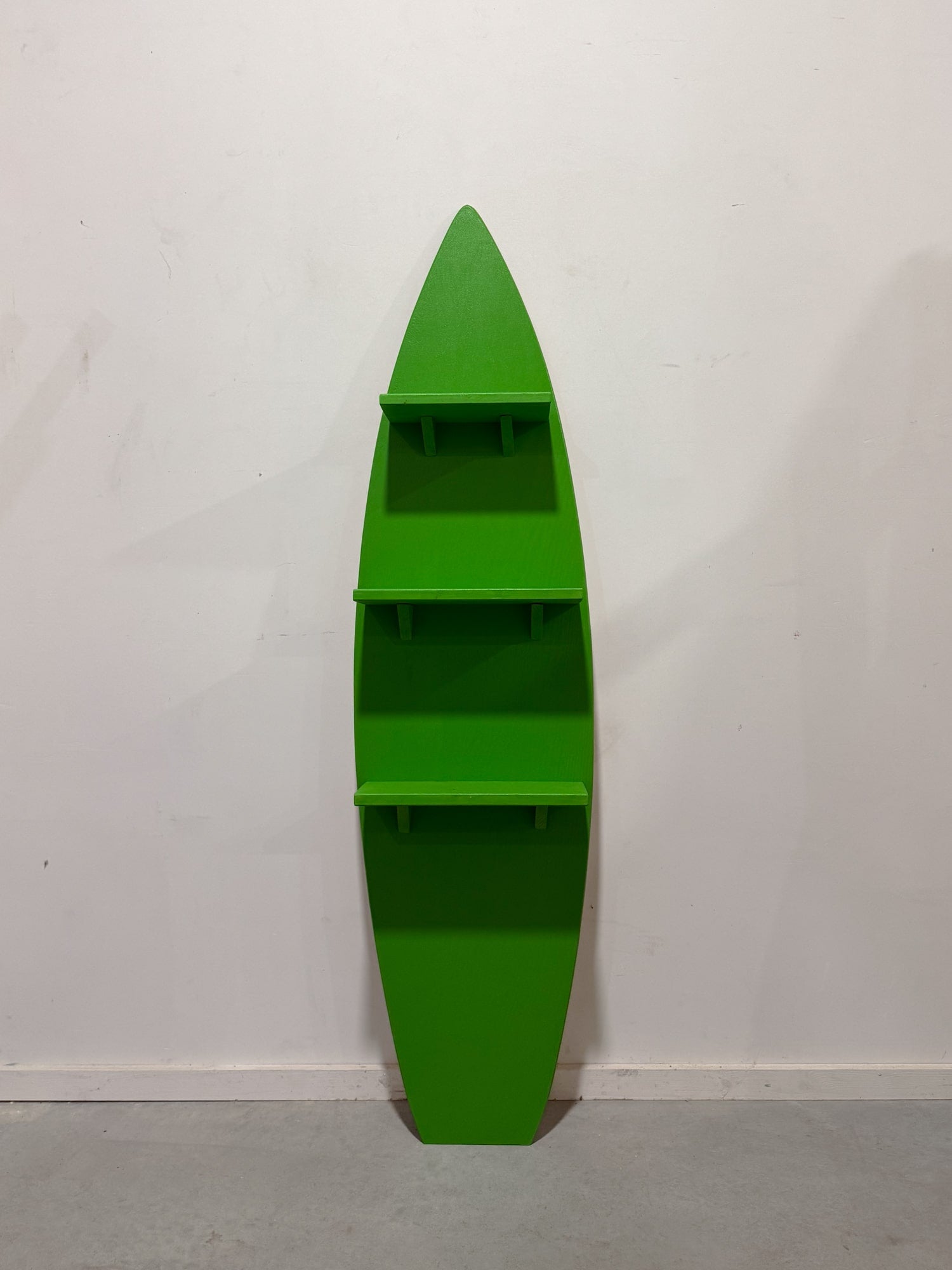 A decorative green wooden surfboard with three shelves, perfect for coastal-themed interiors