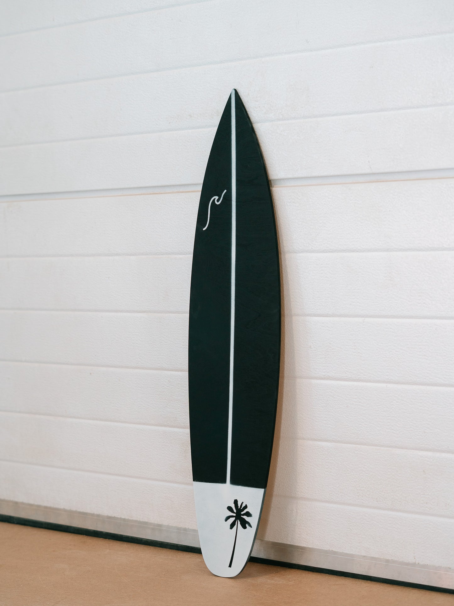 Modern decorative surfboard featuring palm tree artwork on lower section and a wave on the upper left section.