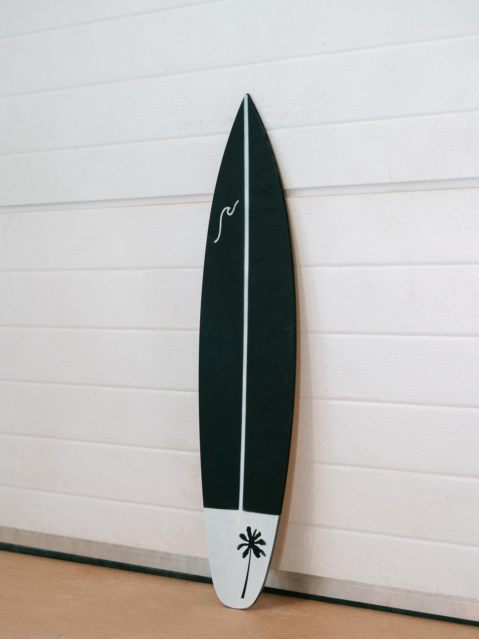 Modern decorative surfboard featuring palm tree artwork on lower section and a wave on the upper left section.