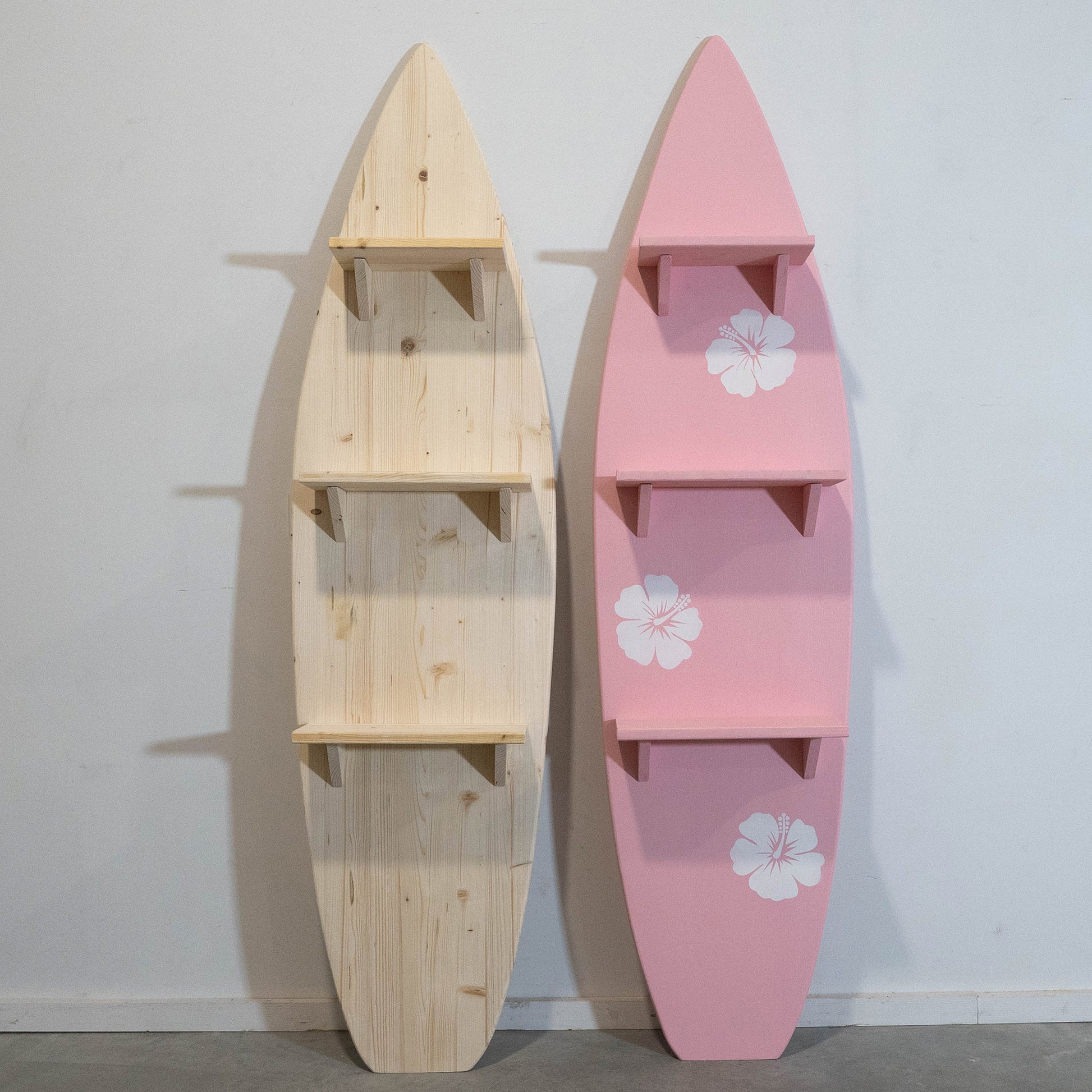 pale pink wooden surfboard with 3 book and record shelves and white hibiscus flowers