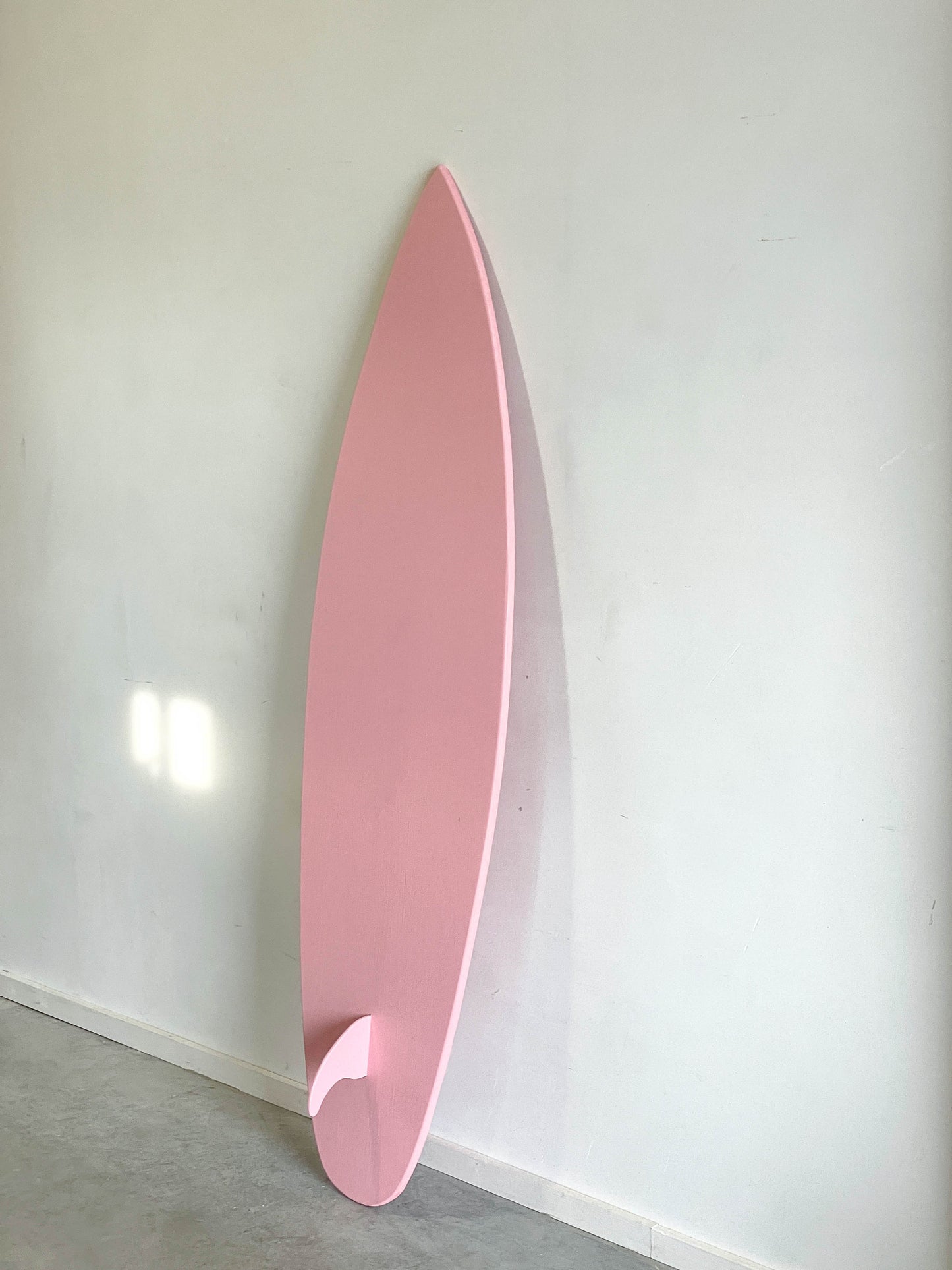 Chic wooden surfboard in a delicate baby pink hue.